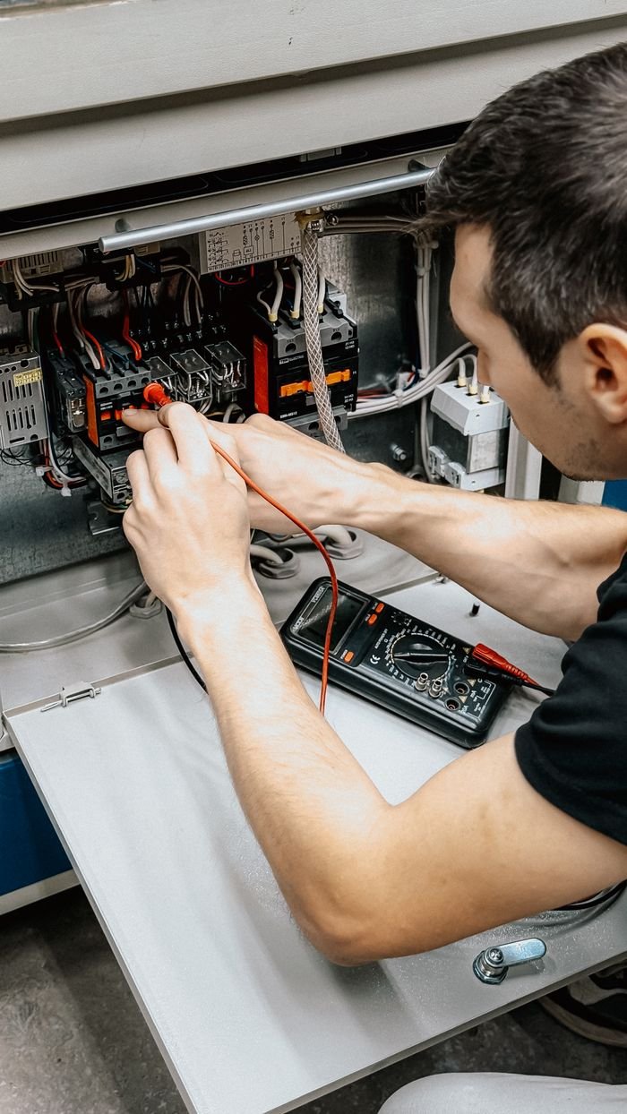 Elektrikas visoje Lietuvoje matuoja įtampą multimetru prie skydinės